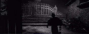 Movie still from “Red Beard” (1965), directed by Akira Kurosawa – A man standing on steps with a fence behind him; Extreme Wide shot, Low angle
