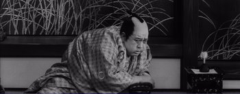 Movie still from “Red Beard” (1965), directed by Akira Kurosawa – An old photo of a man with a strange haircut on his head; Medium shot, Low angle