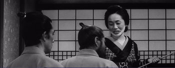 Movie still from “Red Beard” (1965), directed by Akira Kurosawa – An old photo of a man and a woman talking to another man; Medium shot, Over the shoulder angle