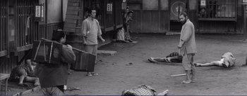 Movie still from “Red Beard” (1965), directed by Akira Kurosawa – A black and white photo of a man standing in front of a woman; Wide shot, High angle