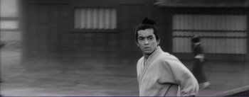 Movie still from “Red Beard” (1965), directed by Akira Kurosawa – A man with a long black hair is standing outside; Close Up shot, Low angle