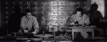 Movie still from “Red Beard” (1965), directed by Akira Kurosawa – Two men are standing in a room with a candle; Medium shot, Low angle