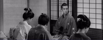 Movie still from “Red Beard” (1965), directed by Akira Kurosawa – A man in a kimono is sitting in front of two other men; Medium shot, Over the shoulder angle