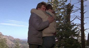 Movie still from “Red Dawn” (1984), directed by John Milius – Two men hugging each other on top of a hill; Medium shot, Low angle