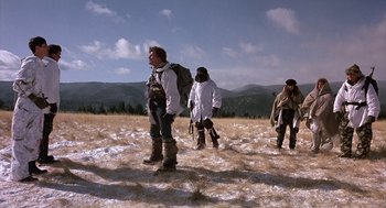 Movie still from “Red Dawn” (1984), directed by John Milius – A group of people standing on top of a snow covered field; Wide shot, Low angle