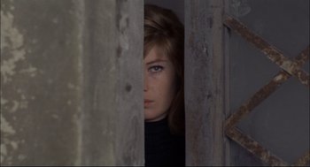 Movie still from “Red Desert” (1964), directed by Michelangelo Antonioni – A young woman looking out from behind a wooden fence; Close Up shot, High angle