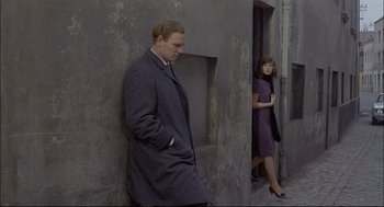 Movie still from “Red Desert” (1964), directed by Michelangelo Antonioni – A man and a woman standing next to each other on the street; Medium shot, Over the shoulder angle