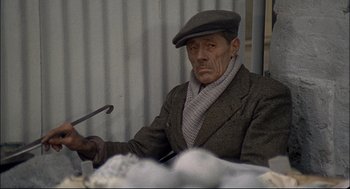 Movie still from “Red Desert” (1964), directed by Michelangelo Antonioni – An older man wearing a hat and a scarf; Medium shot, High angle