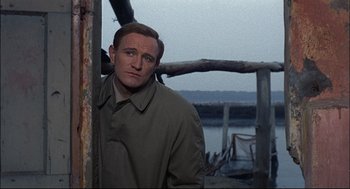 Movie still from “Red Desert” (1964), directed by Michelangelo Antonioni – A man standing next to a wooden structure; Close Up shot, Over the shoulder angle