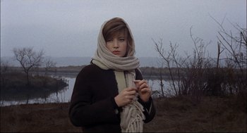 Movie still from “Red Desert” (1964), directed by Michelangelo Antonioni – A young woman wearing a scarf while holding a cigarette; Medium shot, Low angle