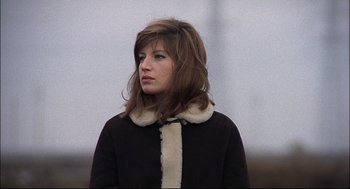 Movie still from “Red Desert” (1964), directed by Michelangelo Antonioni – A young woman wearing a black coat with a fur collar; Close Up shot, Low angle