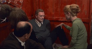 Movie still from “Red Desert” (1964), directed by Michelangelo Antonioni – A group of people sitting on the ground talking to each other; Medium shot, Over the shoulder angle