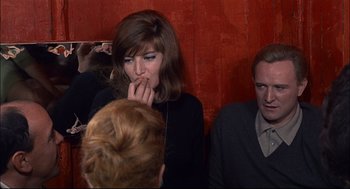 Movie still from “Red Desert” (1964), directed by Michelangelo Antonioni – A woman with her mouth wide open in front of two other people; Medium shot, Over the shoulder angle