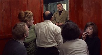 Movie still from “Red Desert” (1964), directed by Michelangelo Antonioni – A group of people standing in front of a mirror; Medium shot, Over the shoulder angle