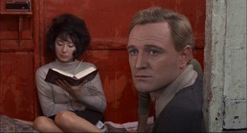 Movie still from “Red Desert” (1964), directed by Michelangelo Antonioni – A man and a woman sitting next to each other in front of an open book; Close Up shot, Low angle