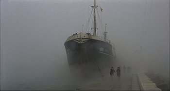 Movie still from “Red Desert” (1964), directed by Michelangelo Antonioni – People walking on the beach near a boat in the fog; Extreme Wide shot, Low angle