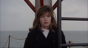 Movie still from “Red Desert” (1964), directed by Michelangelo Antonioni – A woman in a black jacket standing next to a pole; Close Up shot, Low angle