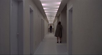 Movie still from “Red Desert” (1964), directed by Michelangelo Antonioni – Two people are walking down a long white hallway; Extreme Wide shot, High angle