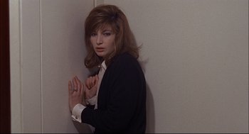Movie still from “Red Desert” (1964), directed by Michelangelo Antonioni – A woman in a black jacket and white shirt leaning against a wall; Medium shot, High angle