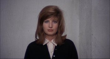Movie still from “Red Desert” (1964), directed by Michelangelo Antonioni – A woman with long brown hair wearing a white shirt and a black jacket; Close Up shot, Low angle