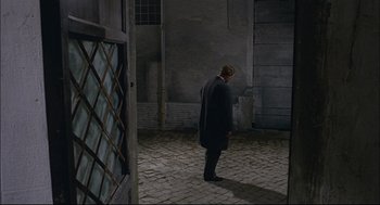 Movie still from “Red Desert” (1964), directed by Michelangelo Antonioni – A man in a suit standing in an empty room; Wide shot, High angle