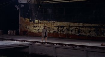 Movie still from “Red Desert” (1964), directed by Michelangelo Antonioni – A woman walking on a train track next to an old ship; Extreme Wide shot, High angle