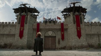 Movie still from “Game of Thrones” (2011), created by D.B. Weiss – A man standing in front of a castle with people on top of it; Extreme Wide shot, Low angle