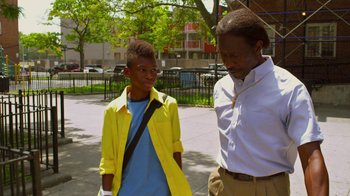 Movie still from “Red Hook Summer” (2012), directed by Spike Lee – A man standing next to a young boy on the sidewalk; Medium shot, Over the shoulder angle