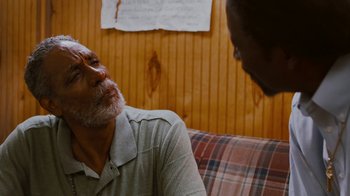 Movie still from “Red Hook Summer” (2012), directed by Spike Lee – A man sitting on top of a couch next to another man; Close Up shot, Over the shoulder angle