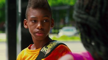 Movie still from “Red Hook Summer” (2012), directed by Spike Lee – A young boy with a yellow shirt and a black bag; Close Up shot, Over the shoulder angle