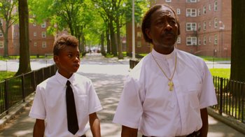 Movie still from “Red Hook Summer” (2012), directed by Spike Lee – A man and a young boy walking down a street; Medium shot, Low angle