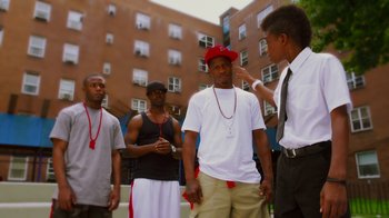 Movie still from “Red Hook Summer” (2012), directed by Spike Lee – A group of young men standing next to each other on the street; Medium shot, Over the shoulder angle