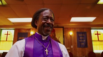 Movie still from “Red Hook Summer” (2012), directed by Spike Lee – A man wearing a purple vest and a cross; Close Up shot, Low angle