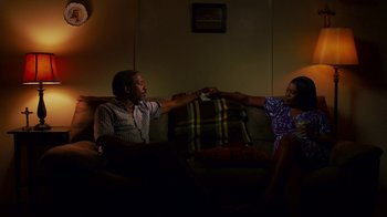 Movie still from “Red Hook Summer” (2012), directed by Spike Lee – A man and a woman sitting on a couch arm in arm; Medium shot, Low angle