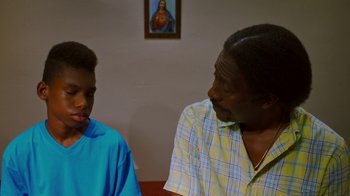 Movie still from “Red Hook Summer” (2012), directed by Spike Lee – A man sitting next to another man in a room; Close Up shot, Over the shoulder angle