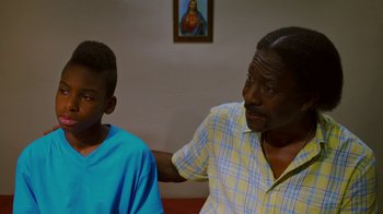 Movie still from “Red Hook Summer” (2012), directed by Spike Lee – A man sitting next to a young boy in front of a painting; Close Up shot, Over the shoulder angle