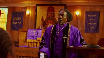 Movie still from “Red Hook Summer” (2012), directed by Spike Lee – A man in a purple and yellow robe standing in front of a podium; Medium shot, Low angle