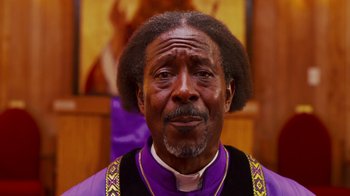 Movie still from “Red Hook Summer” (2012), directed by Spike Lee – A man in a priest's outfit is looking at the camera; Close Up shot, Low angle