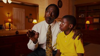 Movie still from “Red Hook Summer” (2012), directed by Spike Lee – An older man and a young boy sitting in a living room; Medium shot, Over the shoulder angle