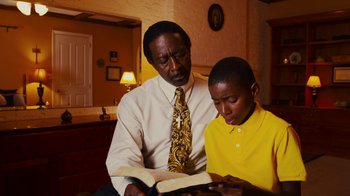 Movie still from “Red Hook Summer” (2012), directed by Spike Lee – A man and a young boy reading a book; Medium shot, Low angle