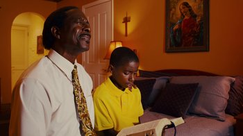Movie still from “Red Hook Summer” (2012), directed by Spike Lee – A man and a young boy singing in a living room; Medium shot, Low angle