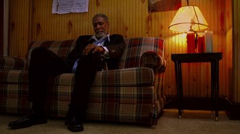 Movie still from “Red Hook Summer” (2012), directed by Spike Lee – An older man sitting on a couch in a room; Medium shot, Low angle