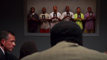 Movie still from “Red Hook Summer” (2012), directed by Spike Lee – A group of men standing next to each other holding signs; Medium shot, Over the shoulder angle