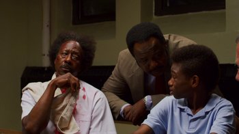 Movie still from “Red Hook Summer” (2012), directed by Spike Lee – A group of people sitting around a table; Medium shot, Over the shoulder angle