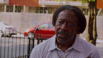 Movie still from “Red Hook Summer” (2012), directed by Spike Lee – An older black man standing in front of a red car; Close Up shot, Low angle
