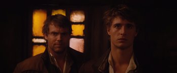 Movie still from “Red Riding Hood” (2011), directed by Catherine Hardwicke – A couple of men standing next to each other in front of a window; Close Up shot, Over the shoulder angle