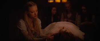 Movie still from “Red Riding Hood” (2011), directed by Catherine Hardwicke – A woman sitting in front of a bed with other women; Close Up shot, Over the shoulder angle