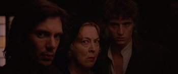 Movie still from “Red Riding Hood” (2011), directed by Catherine Hardwicke – A woman and two young men standing next to each other in a dark room; Close Up shot, Over the shoulder angle