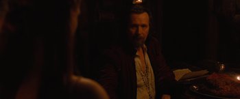 Movie still from “Red Riding Hood” (2011), directed by Catherine Hardwicke – A man sitting in a dark room smoking a cigarette; Medium shot, Over the shoulder angle