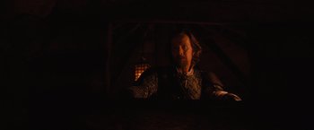 Movie still from “Red Riding Hood” (2011), directed by Catherine Hardwicke – A man with a long beard and a mustache in a dark room; Medium shot, Low angle